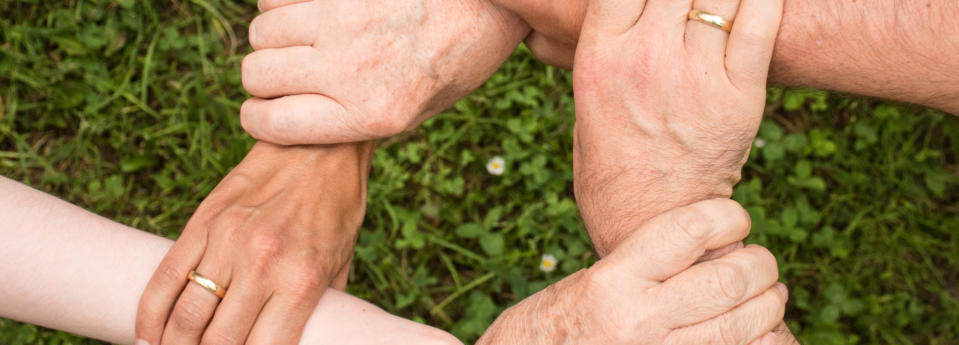 An image of three peoples hands linked together holding each other by the wrist