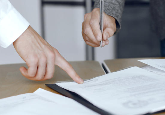 Image of a hand pointing at the position for another person to sign a legal document