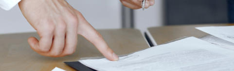 Image of a hand pointing at the position for another person to sign a legal document